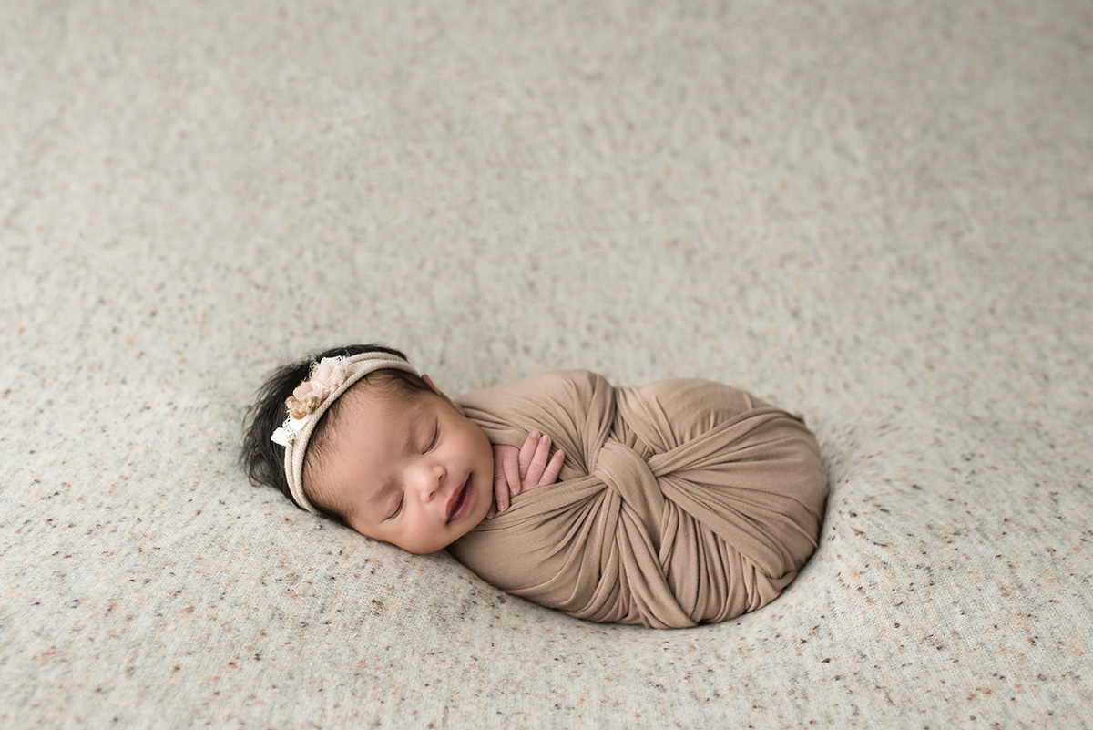 smiling newborn wrapped in blanket