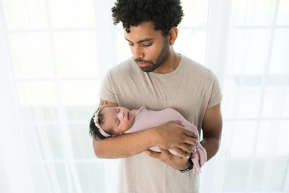 dad holding sleeping baby at posed newborn session