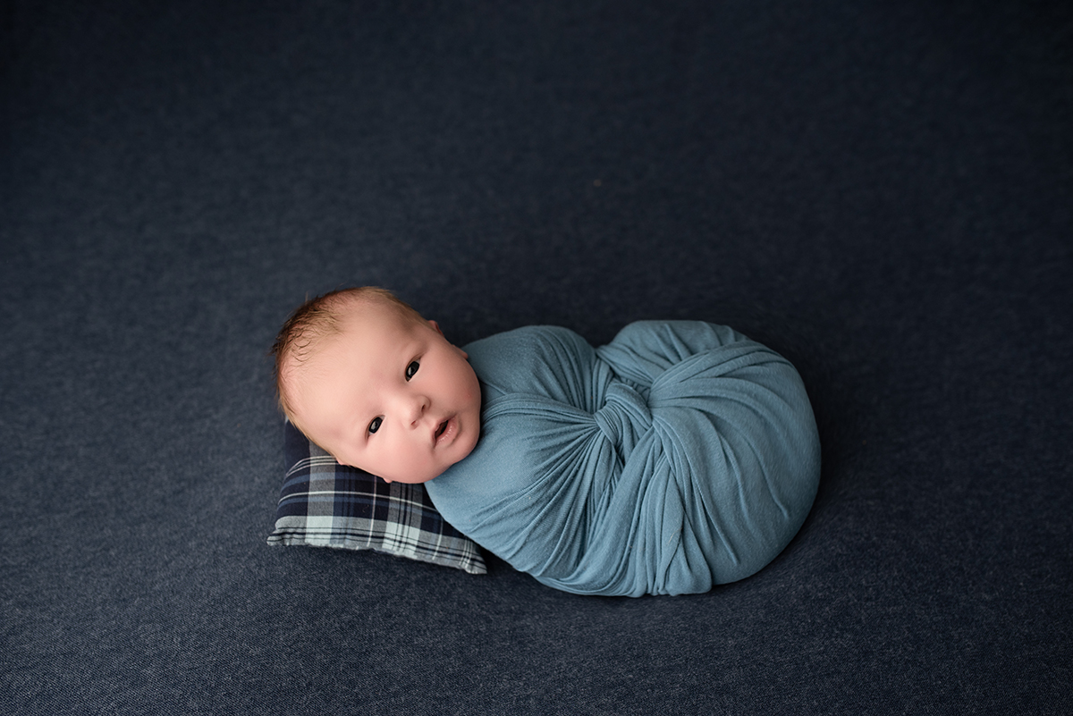 newborn swaddled in blue blanket