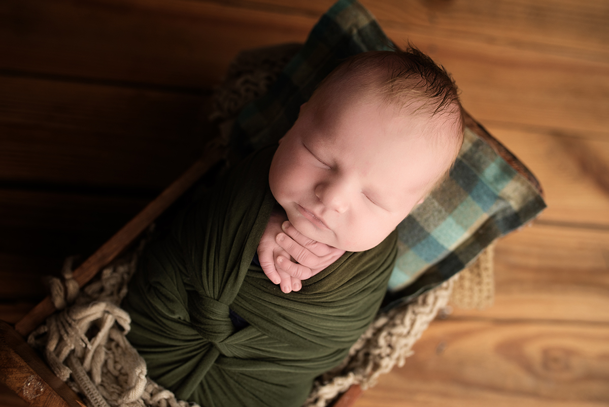 newborn swaddled in green burrito wrap